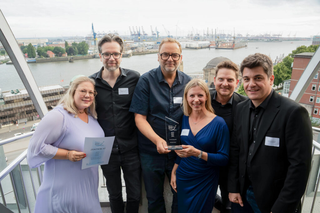 Personen aus dem BFS-Marketingteam und externe Agenturmitarebiter, die einen Award in der Hand halten und in die Kamera lächeln. Im Hintergrund ist Hamburg zu sehen.